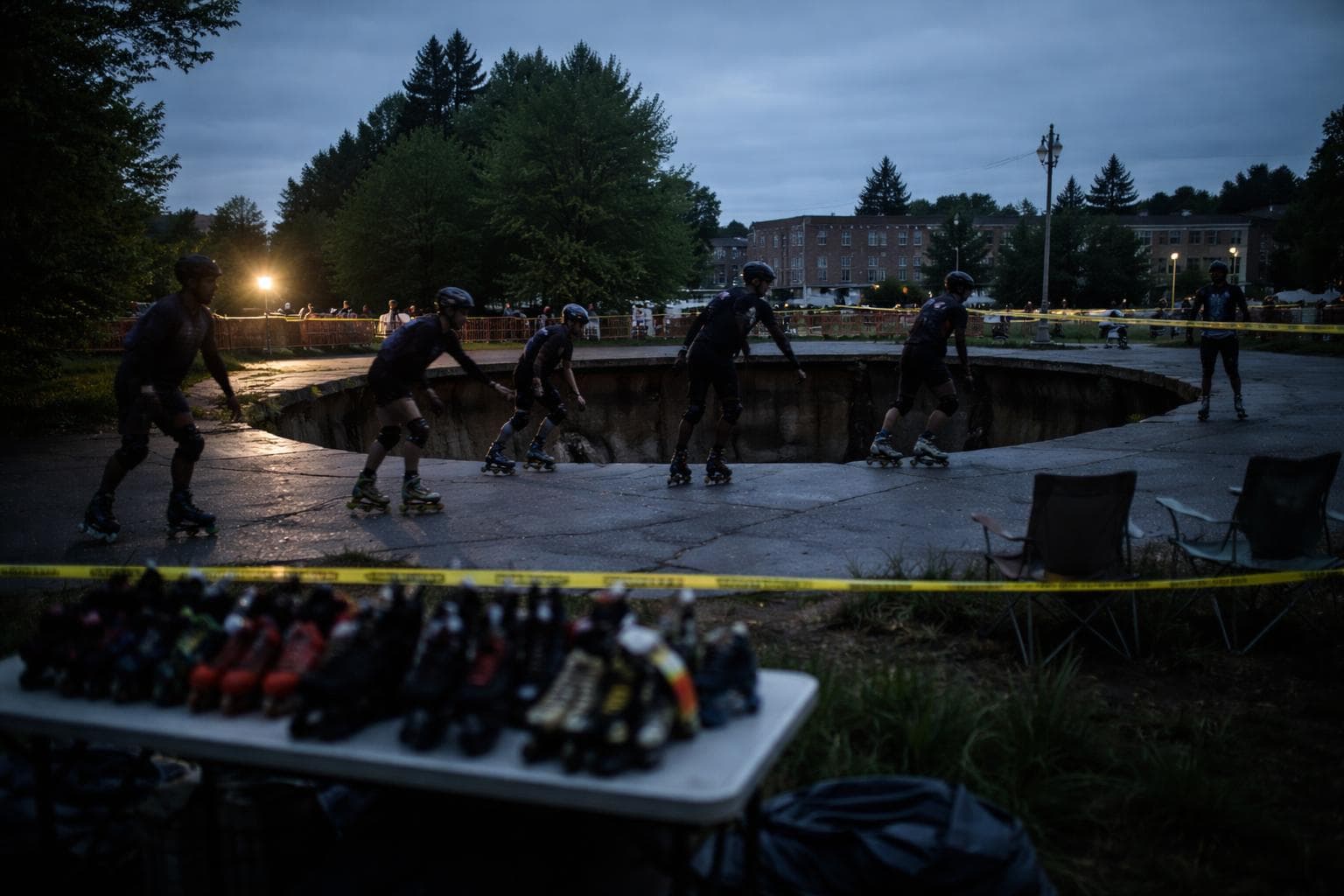 Skaters circle the perimeter of the Third Street Sinkhole during Tuesday evening's session, with rental skates visible on a folding table in the background.